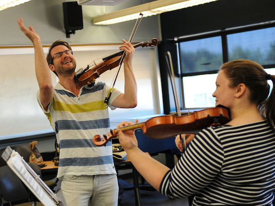 Student playing violin for her professor