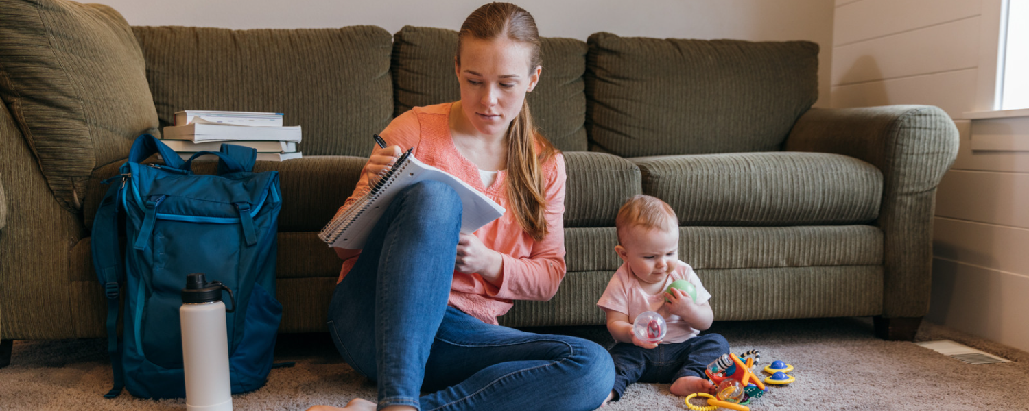 Woman with notebook and young child playing on the floor