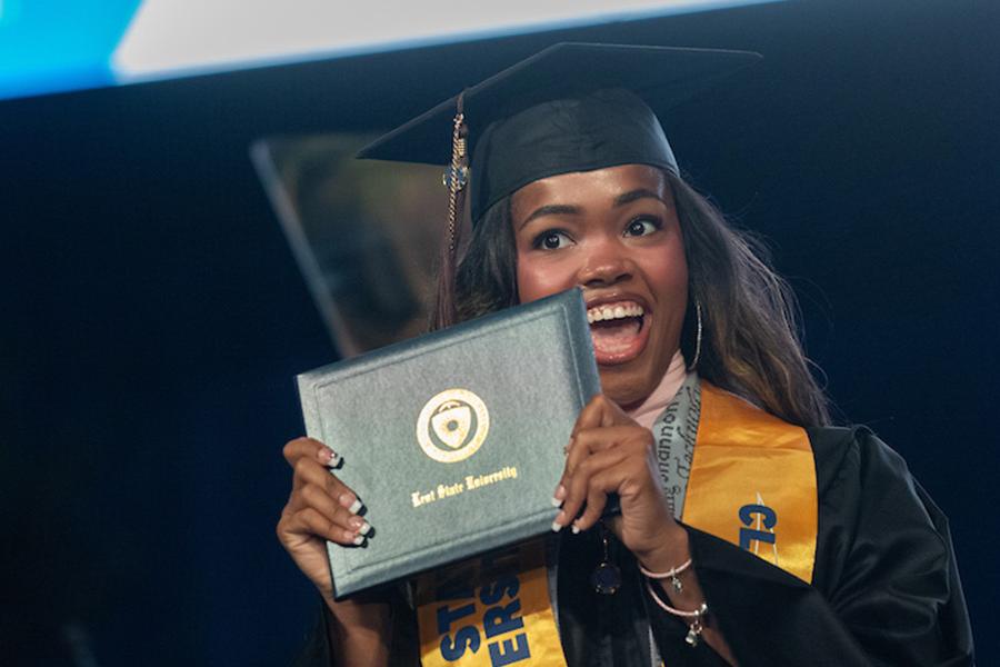 A new ɫҹ University graduate smiles as she holds her diploma during her commencement ceremony. (Photo credit: Bob Christy, ɫҹ University)