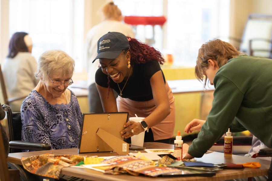 Adedayo Adeagbo (center) volunteering to help older adults at the Tamarack Ridge facility