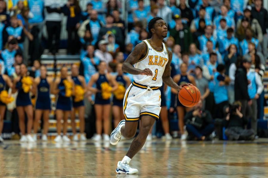 Kent State Golden Flashes men’s basketball player dribbles on the court at the Memorial Athletic and Convocation Center as fans cheer behind him.