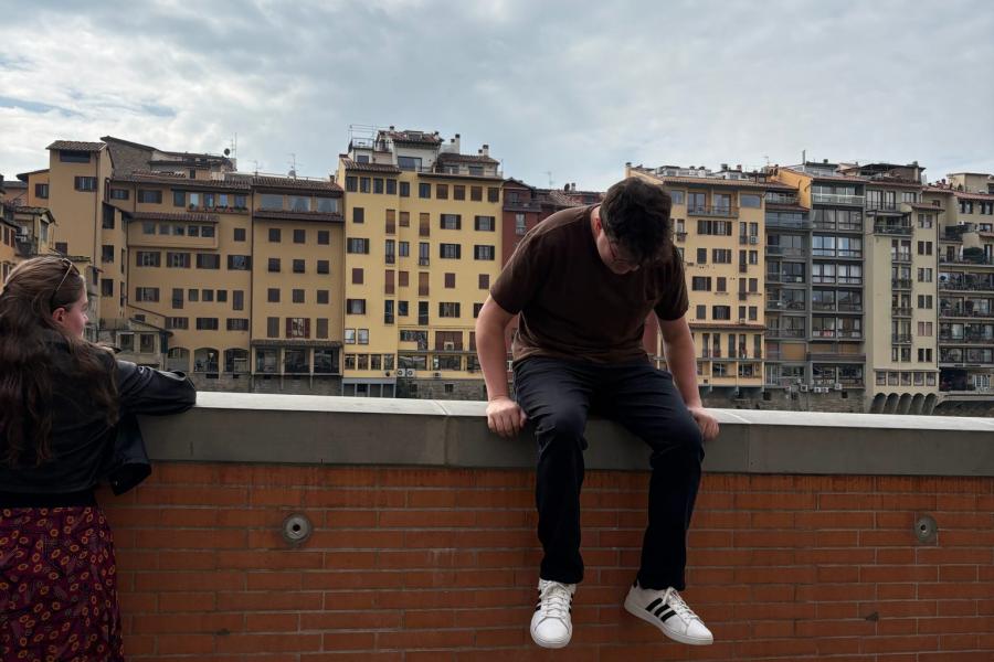 A student sits on the ledge of the Arno river in Florence, Italy.