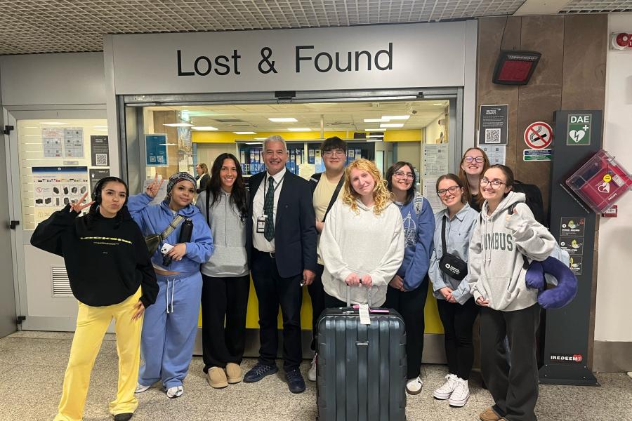 Exploratory students take a photo in front of the lost & Found in the airport.