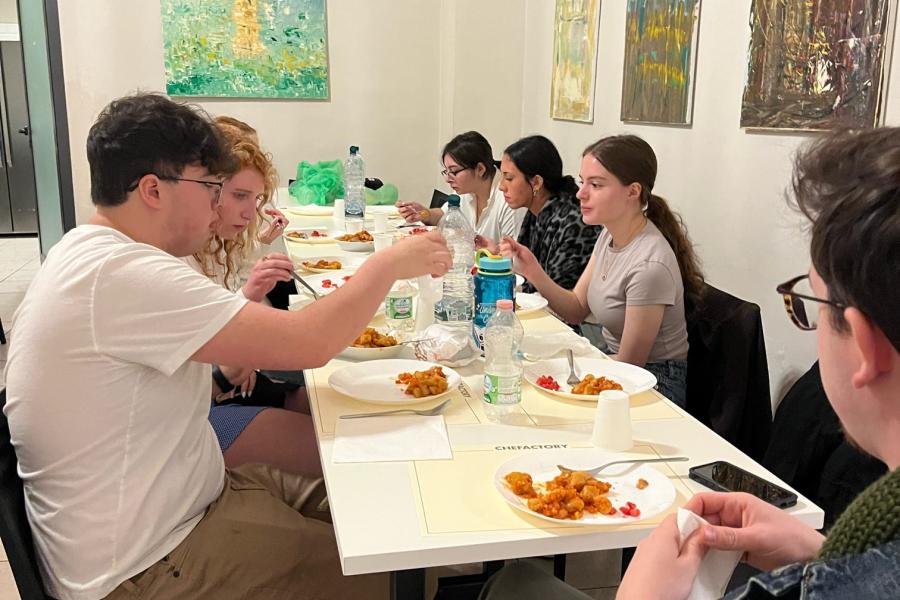 Exploratory students sit around a table eating the food they made in a cooking class in Florence, Italy.