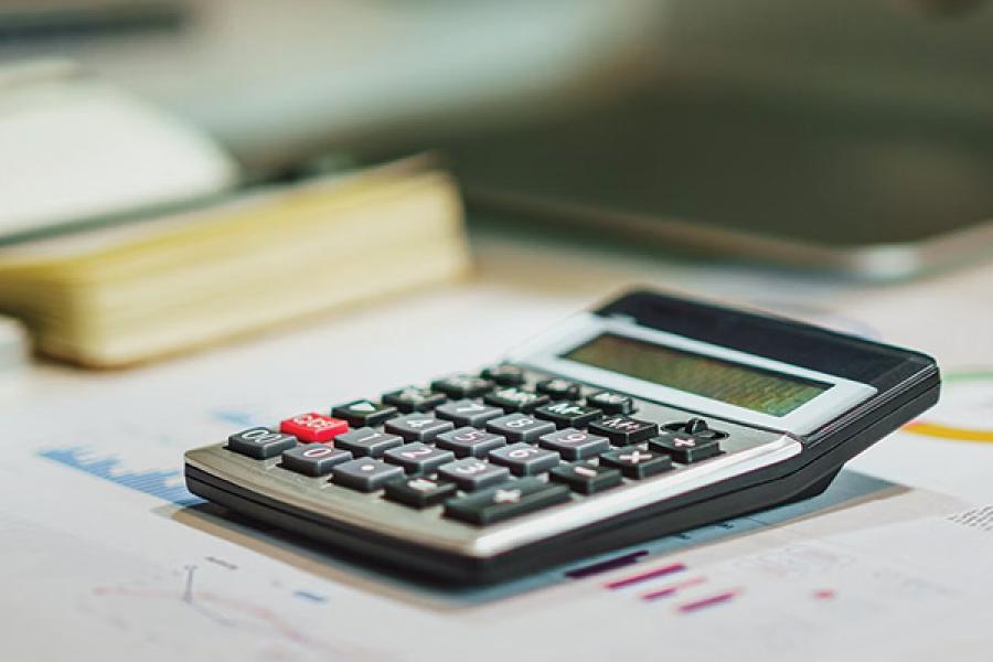 A calculator sits on a desk next to a keyboard.