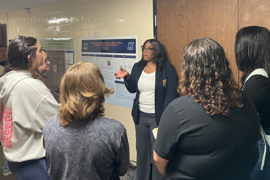 Students gather around a poster presentation in a hallway in White Hall.