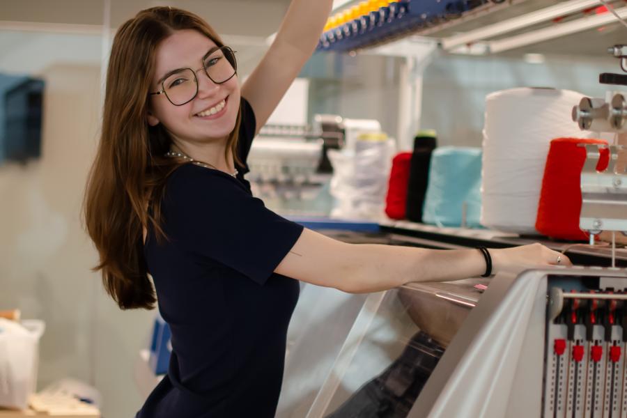 Adelynn Prushing stands in a studio while holding different fabrics.