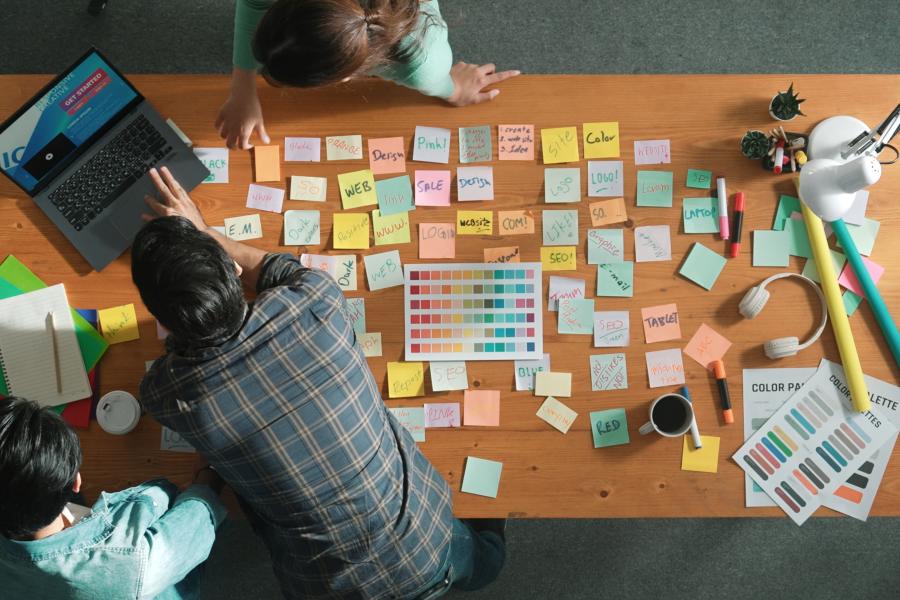 Man working at a desk covered in multi-colored sticky notes