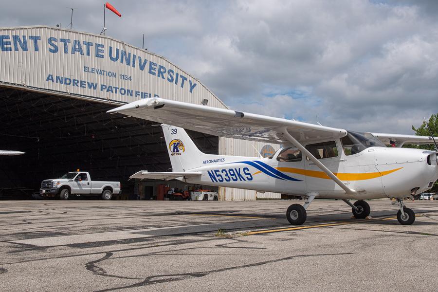 A single-engine airplane parked outside a hangar.
