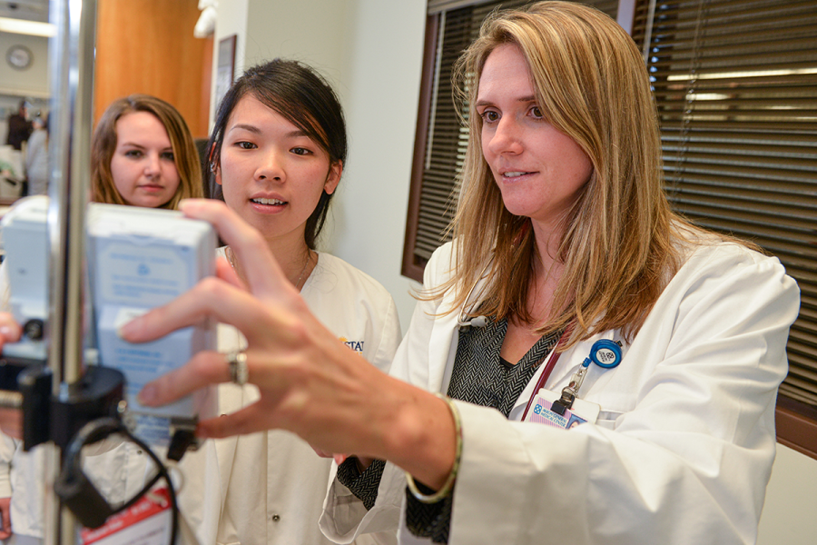 A student in a lab coat inspects a piece of medical equipment.