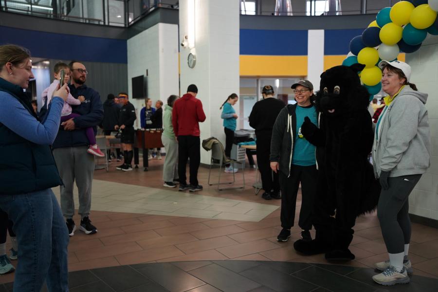 Photo of someone taking a photo of two women with black squirrel mascot