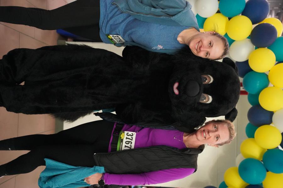 Two women posing with black squirrel mascot