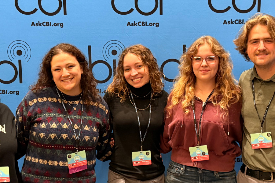Five ����ɫ��ҹ student media participants stand side by side, smiling in front of a blue College Broadcasters Inc. (CBI) step-and-repeat backdrop at a national conference.