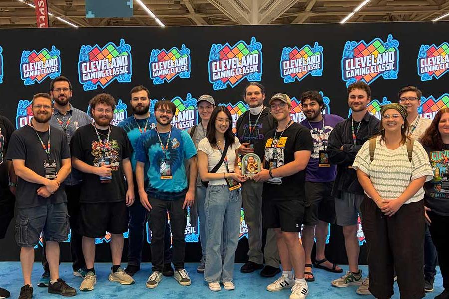 A group of attendees poses together in front of a Cleveland Gaming Classic backdrop at the gaming convention.