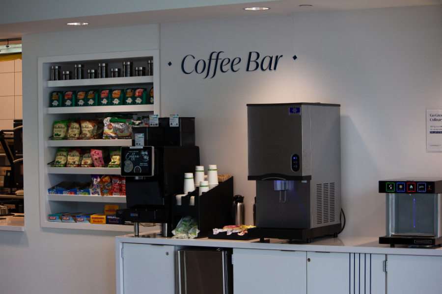 Close up of Commerce Cafe's coffee bar station, with a few different coffee makers and some cups, lids, stirring sticks, and sugar options on the counter