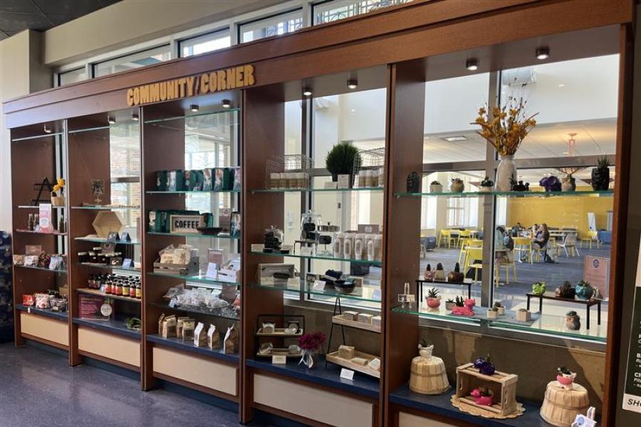 Large display case holding various items/products with the words "Community Corner" at the top of the case