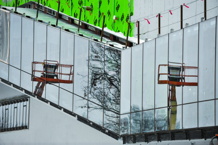 Construction equipment can be seen on a building's reflective facade.