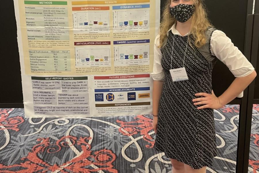 Alena stands next to her thesis research poster "Translating Music into Words: Musical Expression of Figurative Words" at an exhibition in Portland, Oregon.