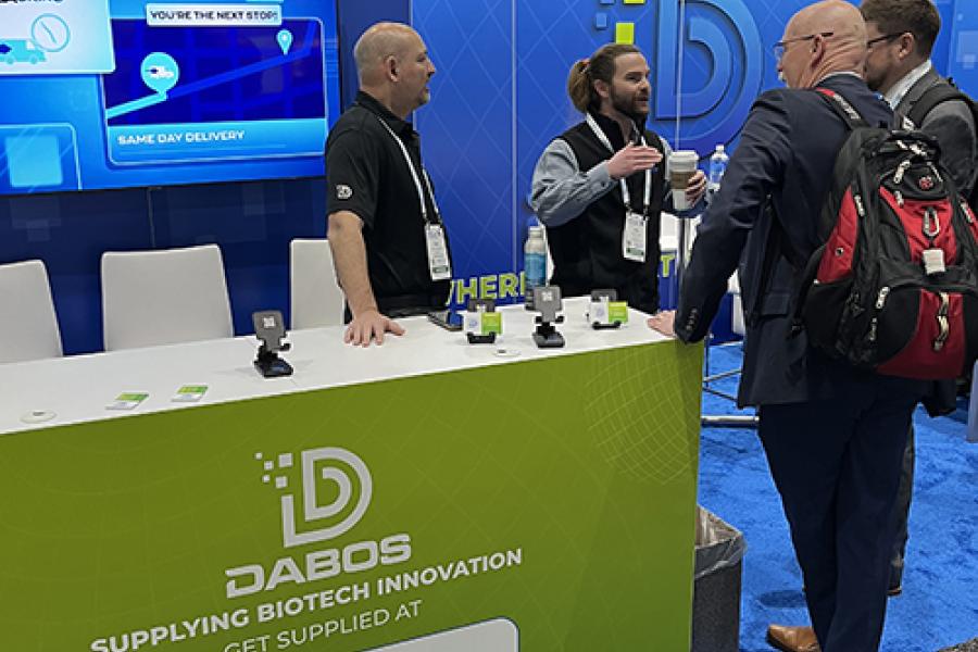 Two DABOS representatives behind a counter answer questions at a conference