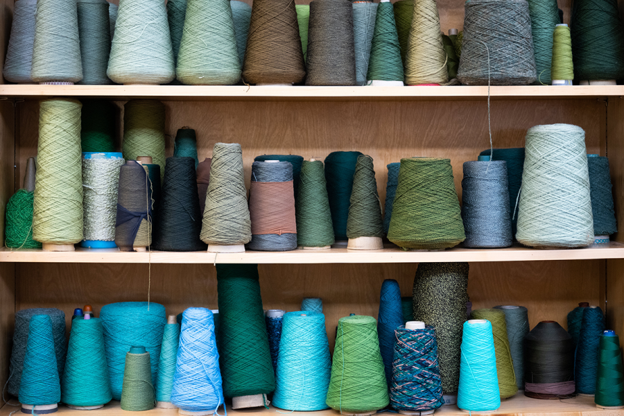 Spools of blue and green yarn sit on a shelf.