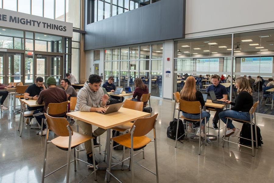 Inside the Aeronautics & Engineering building main atrium where several students are seated at raised tables.