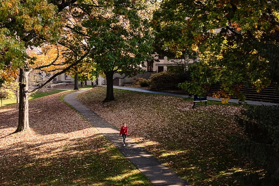 A Kent State student walks through fallen leaves on Front Campus