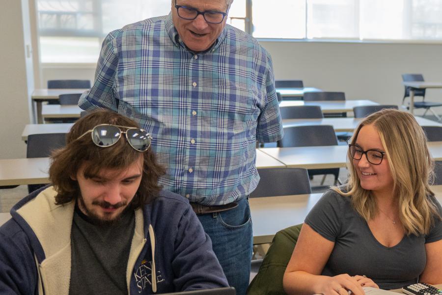 Dr. Micheal Fisch and students viewing laptops in a classroom