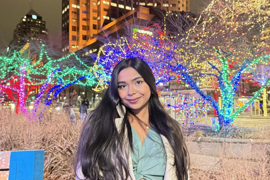 Shashwati Sikder Sharaya posing for picture in front of a building with lights in the background. 