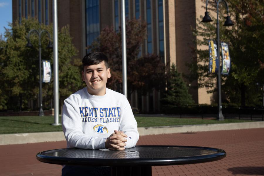 Asadbek Masharipov sitting at a table outside on the ���ϲ����� campus. 