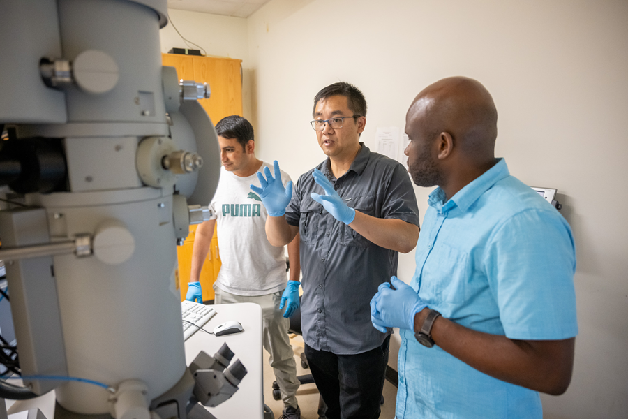 A teacher explains the purpose of a machine to two students.