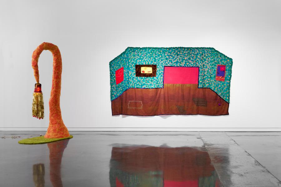 an orange sculpture and a tapestry depicting a room in the gallery