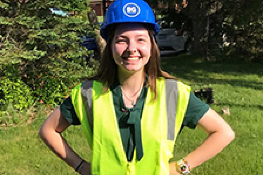 Lilly Kensicki posing in a reflective vest and a blue hard hat.