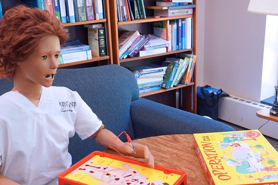 Mani Kin sits in the nursing student lounge all alone with the board game Operation set up on the table in front of her.