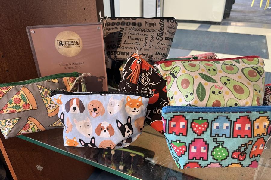 Hand-made zipper bags with various designs placed on a shelf in the Community Corner