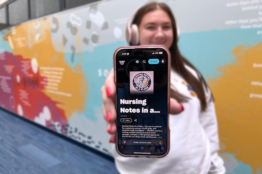 A nursing student wearing headphones holds their phone straight out in front of them with the Nursing Notes in a Flash Podcast displayed on the screen.
