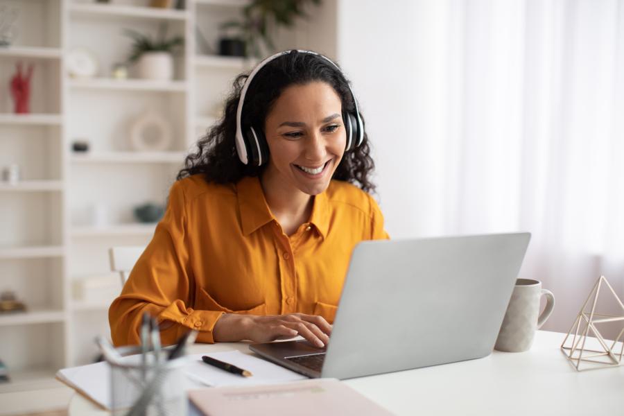 Online training programs image depicting woman on her laptop with headphones