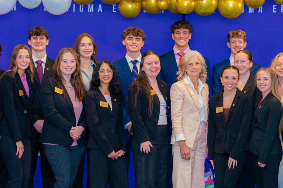 Student members of PSE posing infront of competition banner, pictured with KSU Professor Kelly Blay. 
