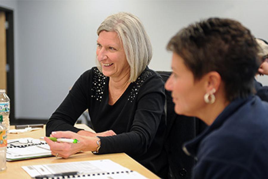 Two women sit and talk in a office space.