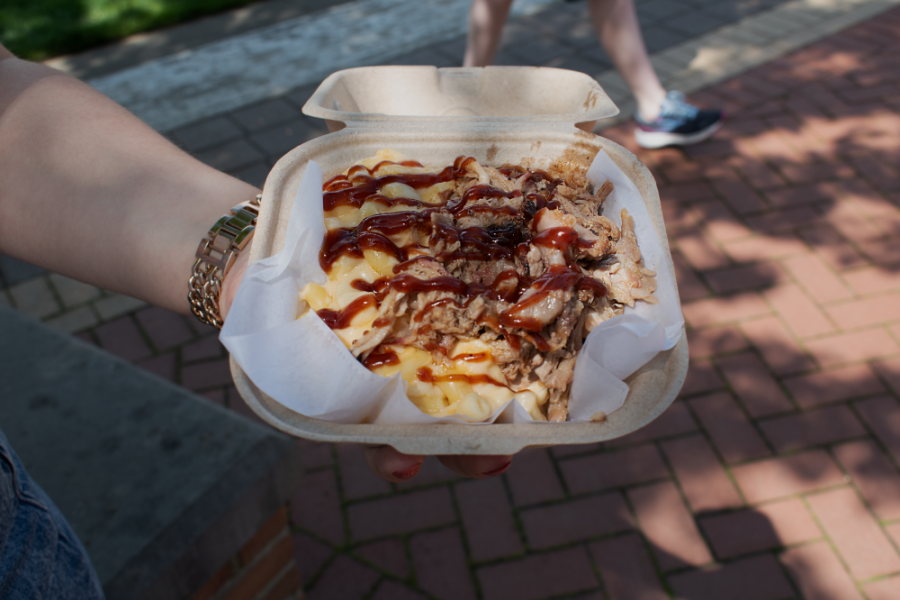 An open container of pulled pork mac n cheese being held by someone out-of-frame