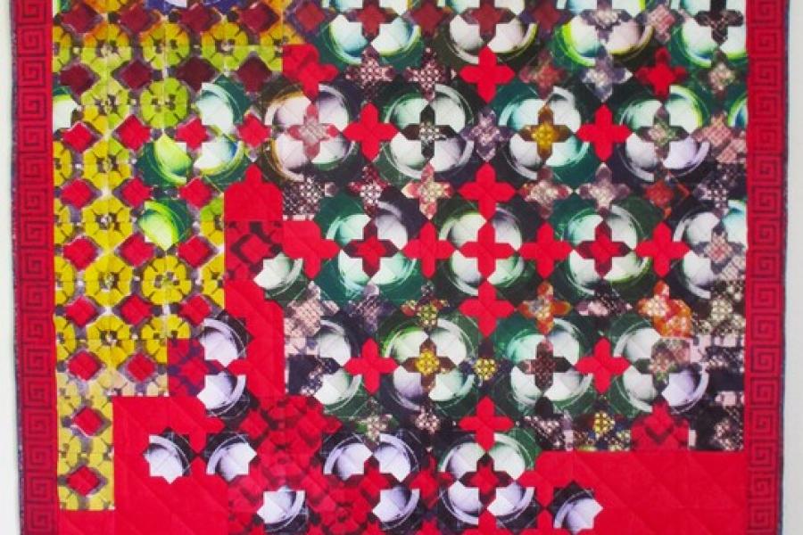 An art quilt composed of solar plate prints, boasting vibrant reds and greens