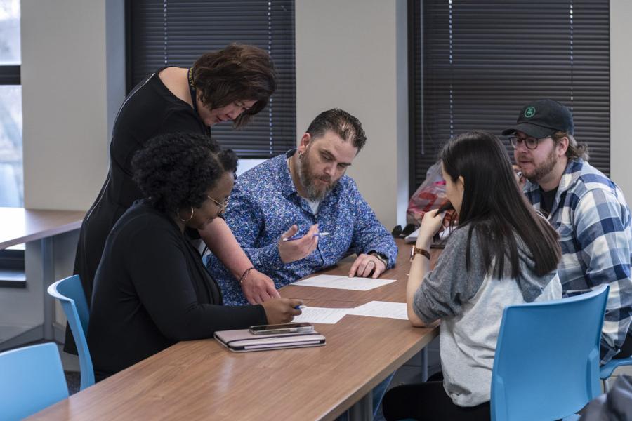 Professor leaning over to speak to grad students
