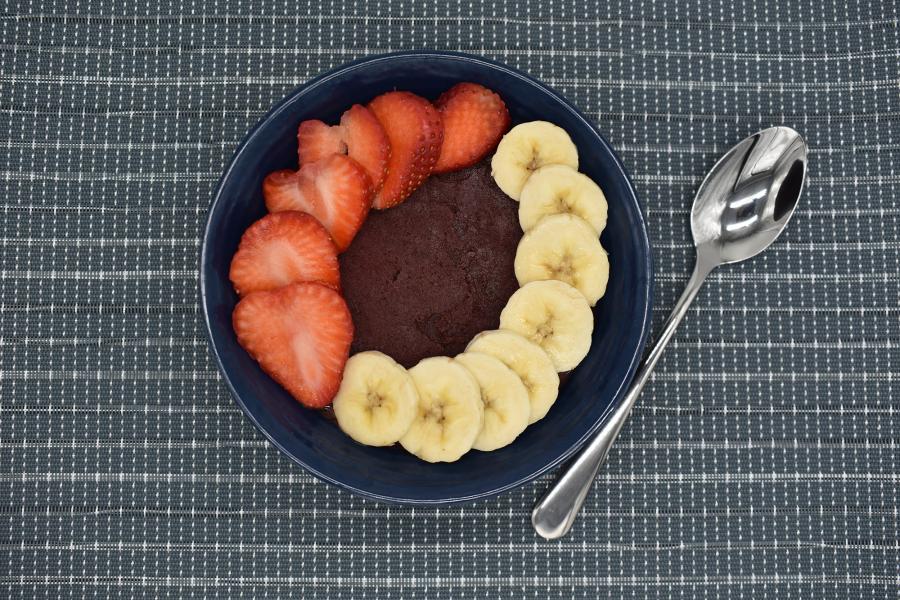 Top view of the Berry Banana Acai Bowl from Commerce Café, one side of the bowl lined with cut strawberries and the other side lined with cut bananas