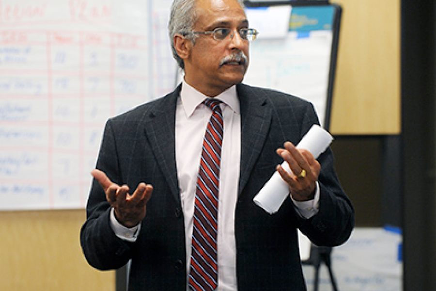 A man in business clothes speaks to a room.