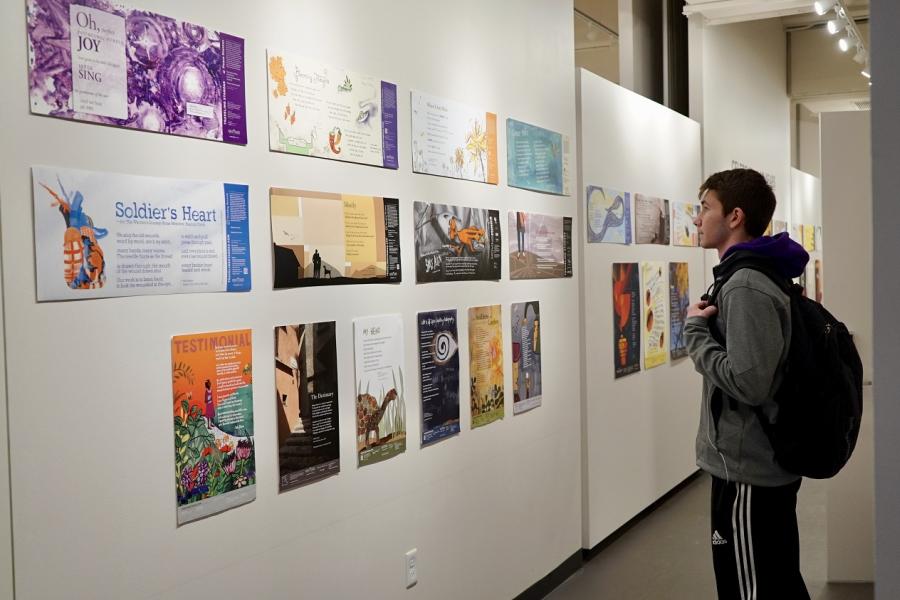Image of a visitor to a gallery looking a wall of poems with illustrations.