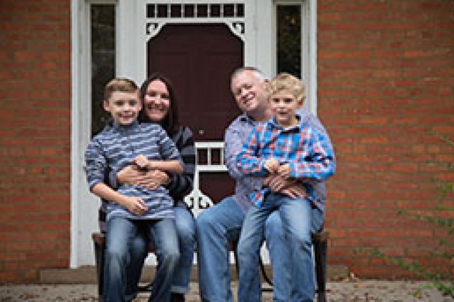 Greg and Darcy, posed and smiling with their two children