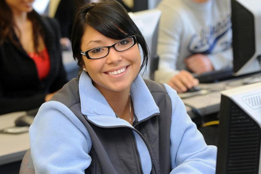 Kent State student in a computer lab smiles at the camera