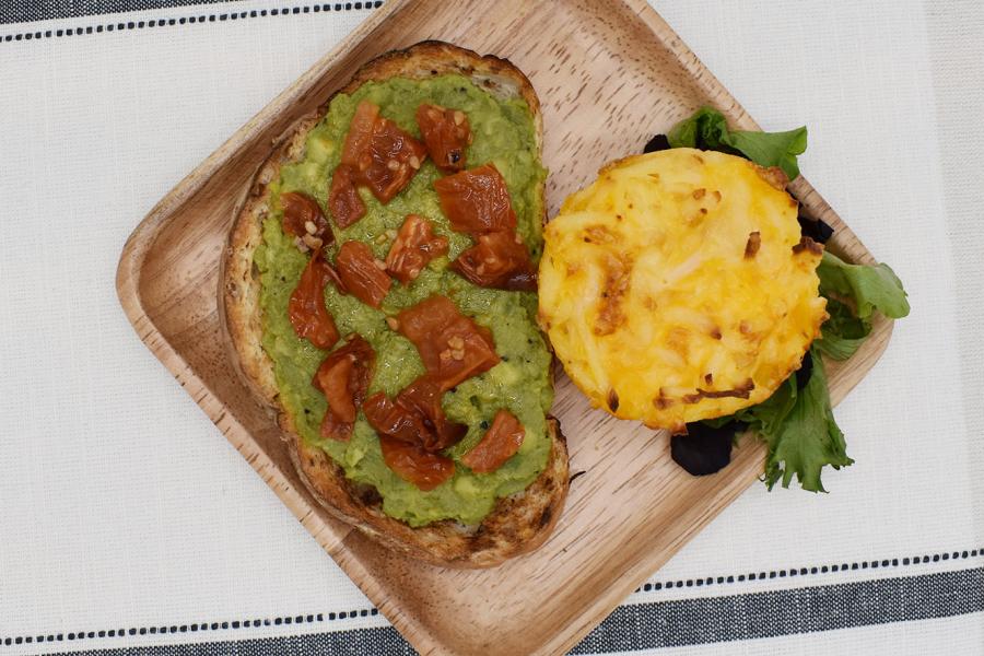 Top view of a plate of Avocado Toast with a Hashbrown on the side