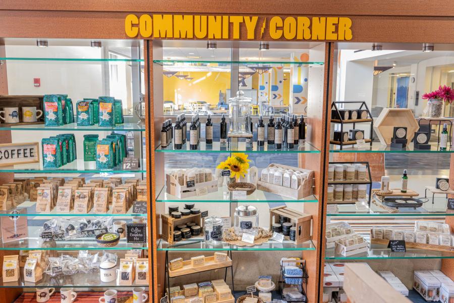 Close up of Community Corner display cabinet, with the words "Community Corner" at the top of the cabinet and several different products lining the shelves