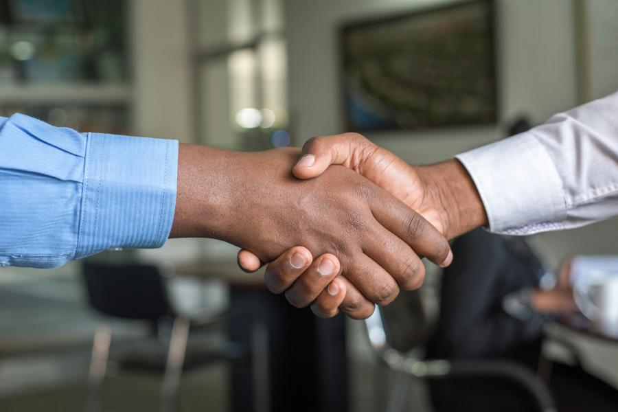 Two people shake hands in an office environment. 