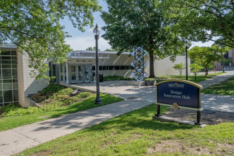 Outside view of the DI Hub's building exterior, including the main entrance doors and a sign reading "Design Innovation Dining"